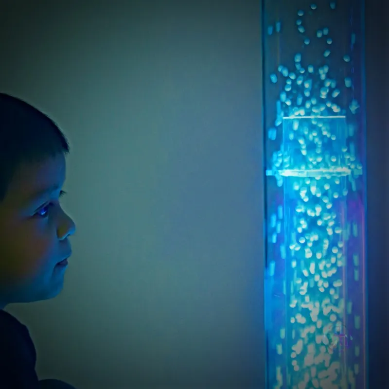 Child gazing at blue bubble sensory lamp